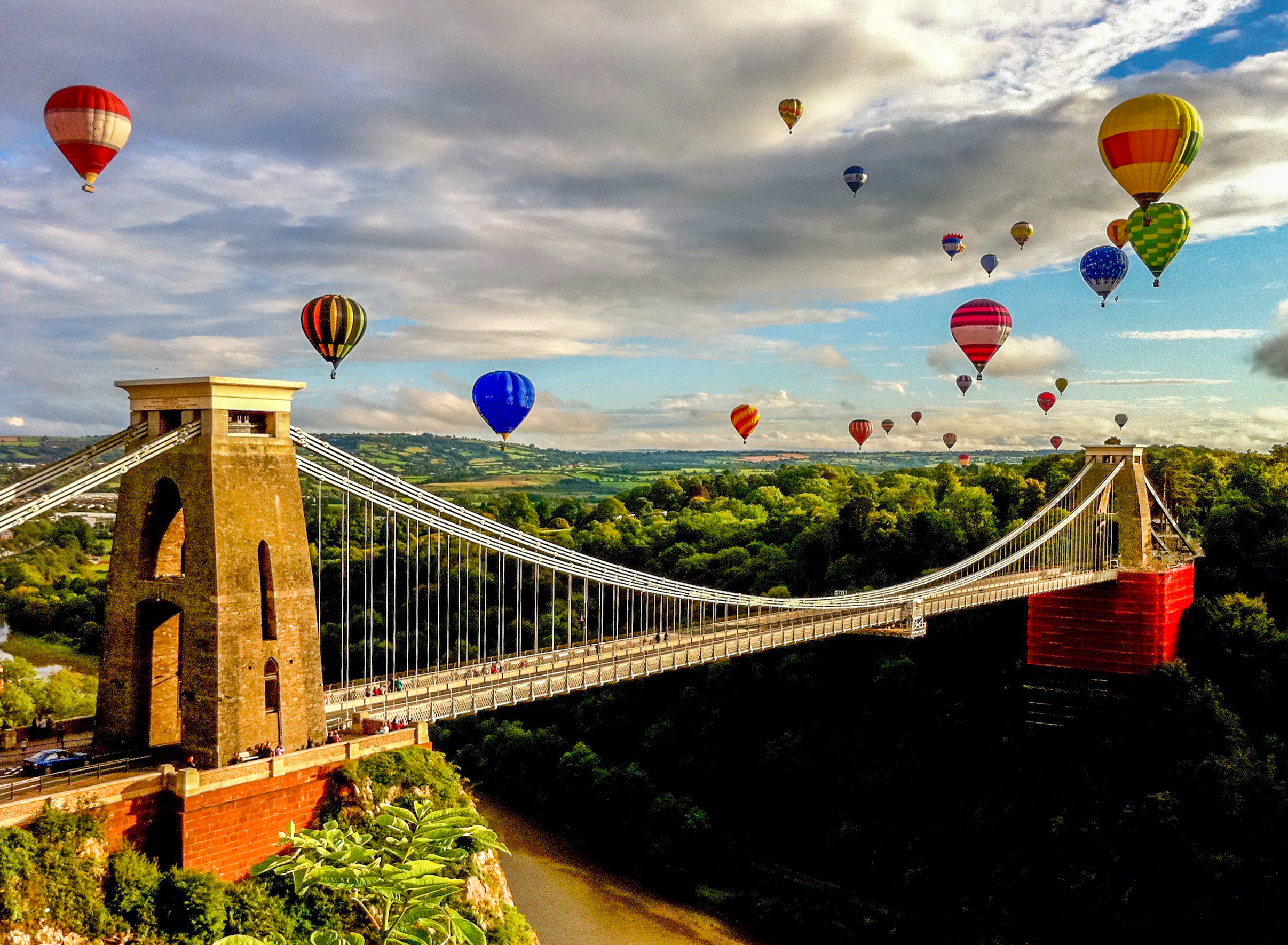 Hot air balloons over suspension bridge in the English countryside